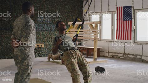 African American Trainer Instructing Soldier During Suspension Training