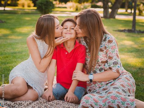 Happy Mother Son And Daughter In The Park Mom And Sister Kiss Their