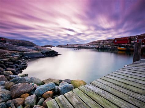 Colorful Houses Near River With Wooden Dock Under Purple Sky In Swedish