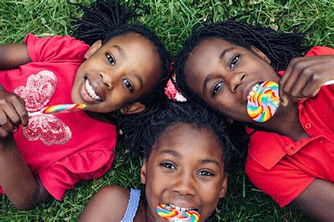 Three African American Girls With Rainbow Lollipops On The Grass Del