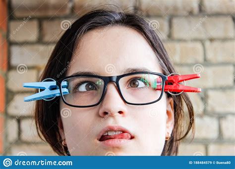 A Girl With Glasses With Slanted Eyes And Clothespins Attached To Her
