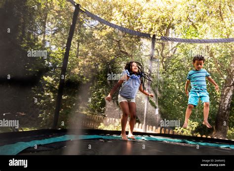 Boy And Girl Jumping On Trampoline Stock Photo Alamy