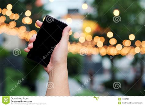 Smart Phone In Hand With Bokeh In Park Background And Have Some Space