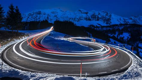 Photography Of Curved Lighting Road Surrounded Snow Covered Mountains