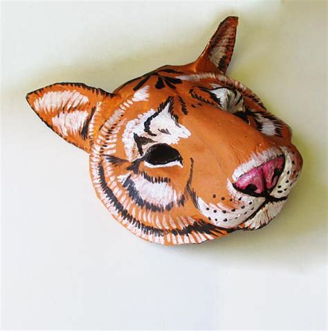 A Paper Mache Of A Tiger S Head On A White Surface With One Eye Open