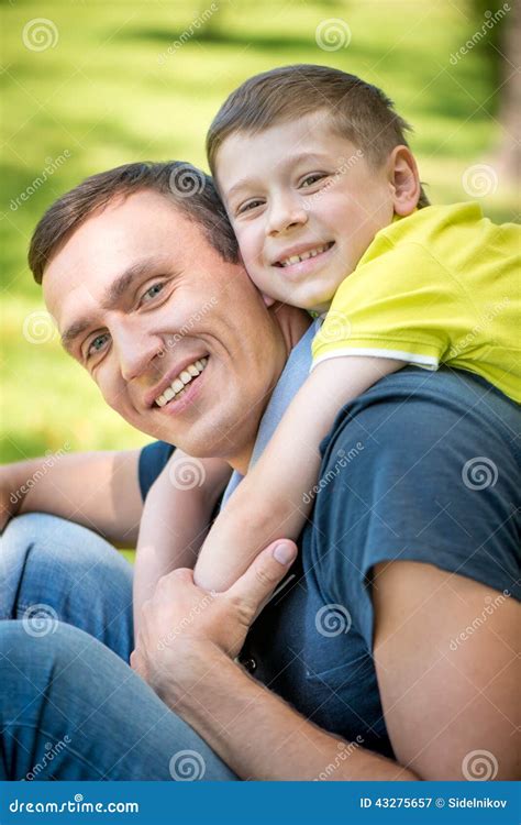 Padre E Hijo Felices Sonrientes Que Abrazan En El Parque Imagen De