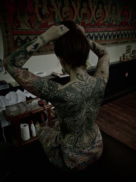 A Woman With Tattoos On Her Back And Arms