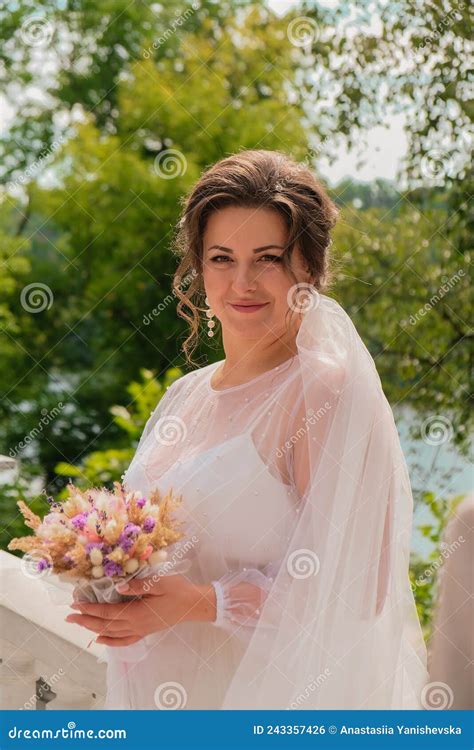 beautiful smiling bride in traditional white wedding dress holding bouquet of dry homemade