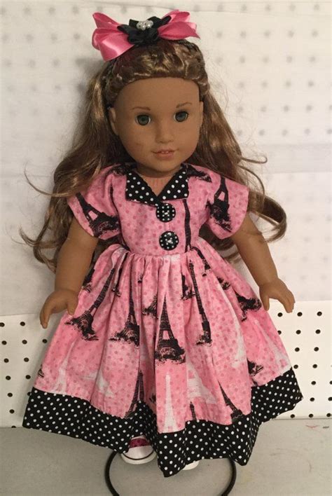 the doll is wearing a pink dress with black polka dots and a bow on her head