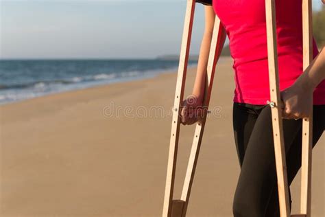 Patient Woman Using Crutches Support Broken Legs For Walking Beach