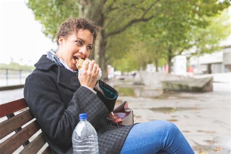 Young Woman Seated On A Bench Having Lunch In London Stock Image