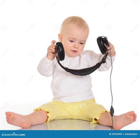 Bebé Que Juega Con Los Auriculares En El Fondo Blanco Foto De Archivo
