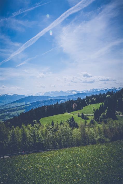 Green Grass Field Under Grey Clear Sky Overlooking Mountains · Free