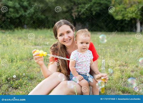 Feliz Madre E Hija Soplando Burbujas En El Parque Foto De Archivo