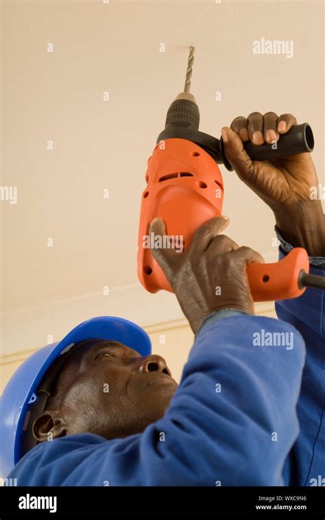 african american construction worker handyman carpenter drilling with electrical power tool