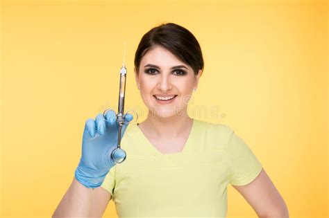Closeup Photo Of Female Dentist Holding Oral Syringe Isolated Over The Yellow Backgrownd Stock