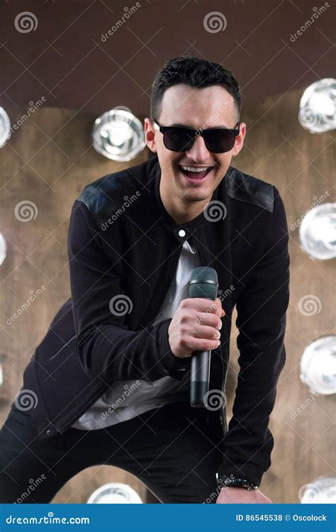 Male Singer In Sunglasses With Microphone Singing In Projectors Stock