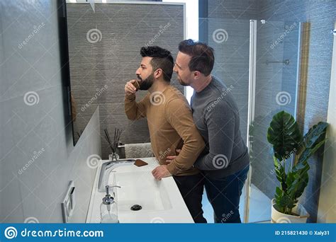 Gay Married Hugging In The Bathroom Of Their Home While Combing Their