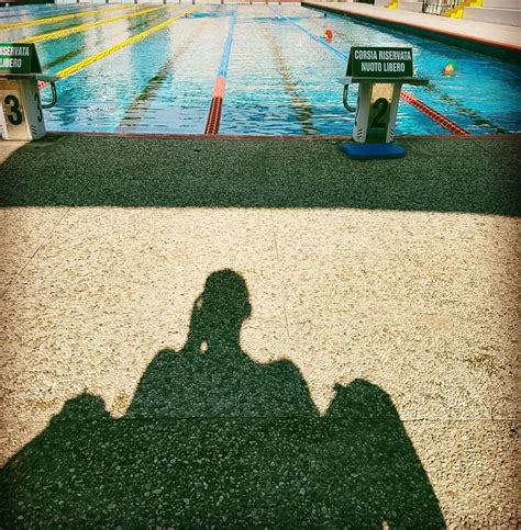 The Shadow Of A Person Sitting In Front Of A Swimming Pool