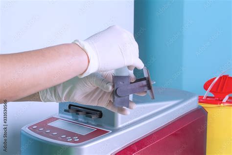 hands in gloves load slide glasses with patient biopsy sections in high throughput automatic