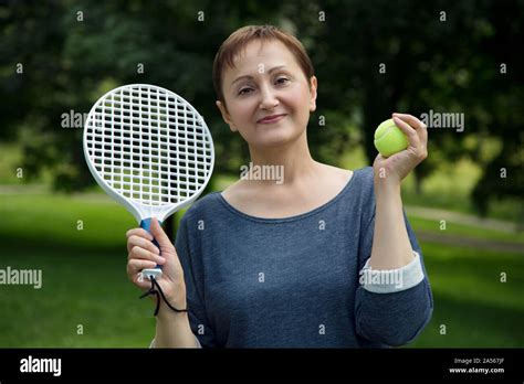 Woman Playing Tennis Portrait Of Active Middle Aged Woman Holding A Racket And A Tennis Ball