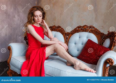 Slim Beautiful Woman In Red A Line Dress Lying On Sofa In Luxury