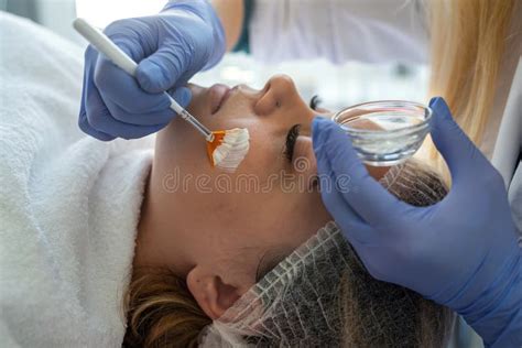 Cosmetologist Applying Healing Cream On Female Client Face Skin In