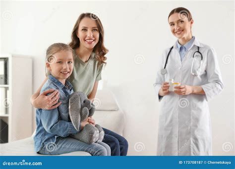 Mother And Daughter Visiting Pediatrician Doctor Working With Patient