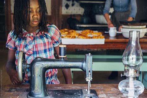 African American Girl Looking At A Vintage Sewing Machine Del
