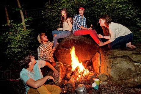 Friends Roasting Marshmallows Over Forest Campfire Stock Photo Dissolve