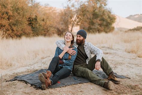 happy couple laughing in field by stocksy contributor leah flores stocksy