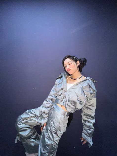 A Woman In Silver Jumpsuits Is Posing For The Camera With Her Hands On