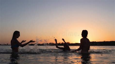 Happy Wet Girls Silhouettes In Bikini Have Fun Splashing Water To Each Other On Sunset Female