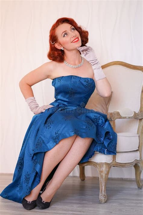 Mannered Beautiful Vintage Woman Dressed In Blue Retro Dress Sitting On A Chair Alone And