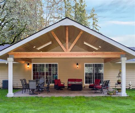 A Covered Patio With Chairs And Tables In The Grass Near A House On A