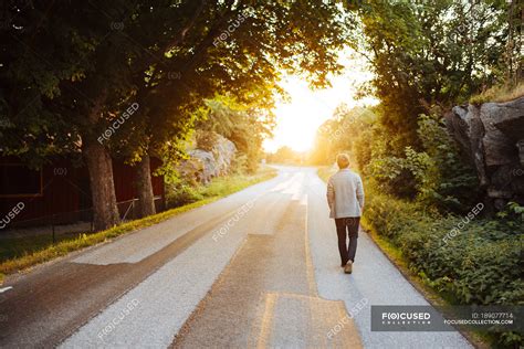 Rear View Of Man Walking On Road At Sunset — Scandinavia Sweden