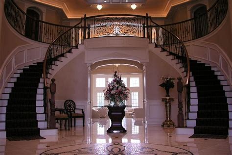Entryway To A Luxury Home With Grand Staircase And Unique Tiled Floor