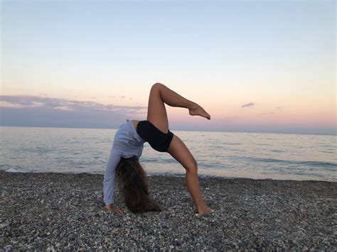 A Woman Doing A Handstand On The Beach In Front Of The Ocean At Sunset