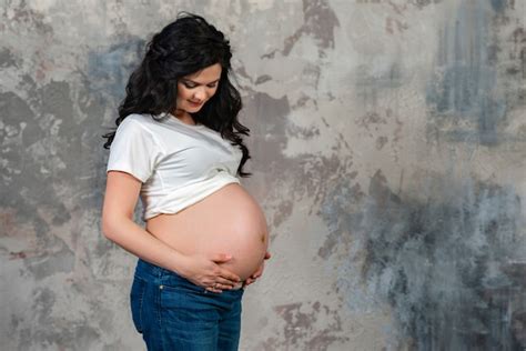 Premium Photo A Half Length Portrait Of Pregnant Woman Looking At Her Bare Tummy