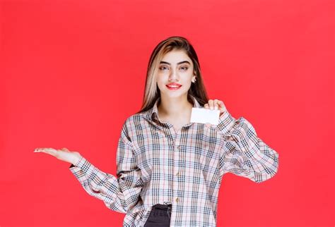 Fille En Chemise à Carreaux Tenant Une Carte De Visite Et Pointant Vers