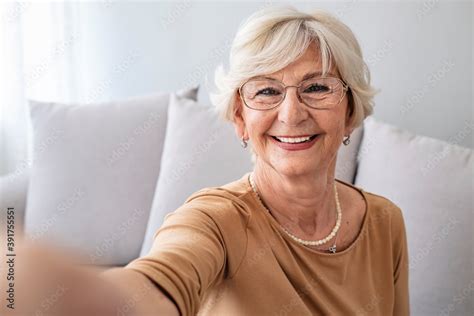 grandma taking selfies at home in the livingroom close up portrait of happy cheerful delightful