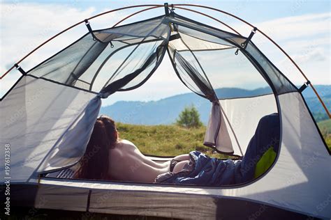 Back View Of Attractive Naked Female Traveller Lying In Tent In Sleeping Bag Enjoying Summer