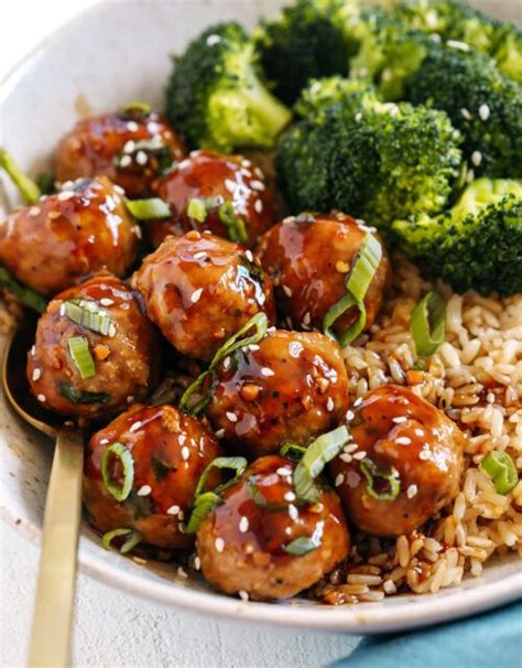 A White Bowl Filled With Meatballs And Broccoli On Top Of Brown Rice