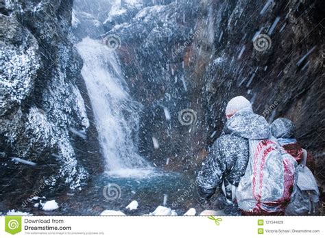 Two People Near A Waterfall In Snow Storm In Iceland Stock Image