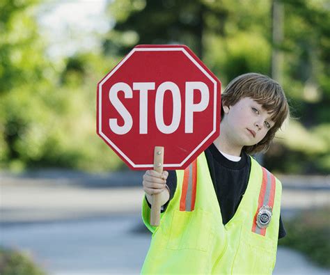 Portrait Of A Young Boy Crossing Guard Standing On The Road Holding A