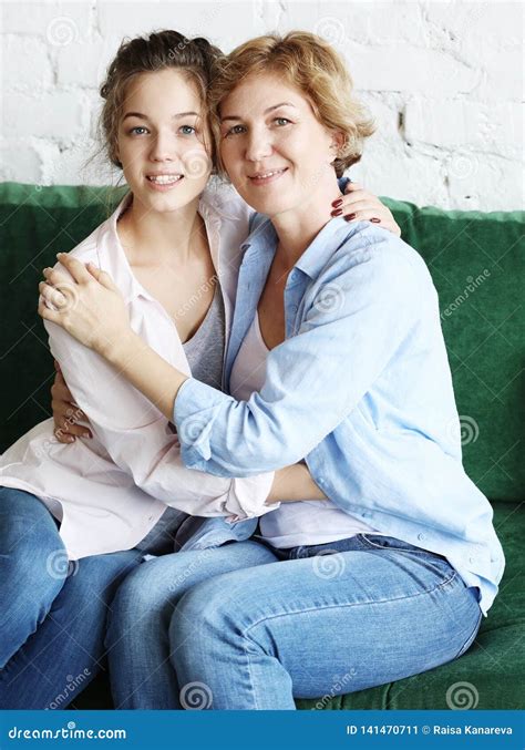 Beautiful Senior Mom And Her Adult Daughter Are Hugging Looking At Camera And Smiling Stock