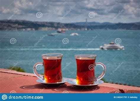 Two Cups With Black Tea On Saucers Stand In A Photo Of The Bosphorus In