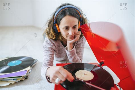 Young Woman Listening To Vinyl On Record Player With Headphones On