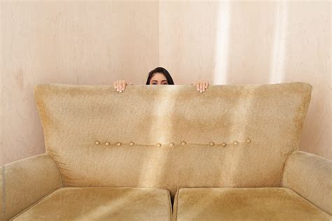 Young Woman Hiding Behind A Retro Couch Stocksy United