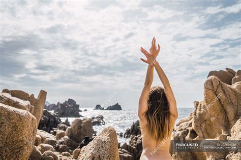 Vue de dos de femme nue avec les mains en l air debout et s étendant